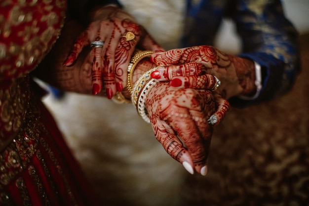 Dama de honor ayuda a la novia india a ponerse joyas en la mano