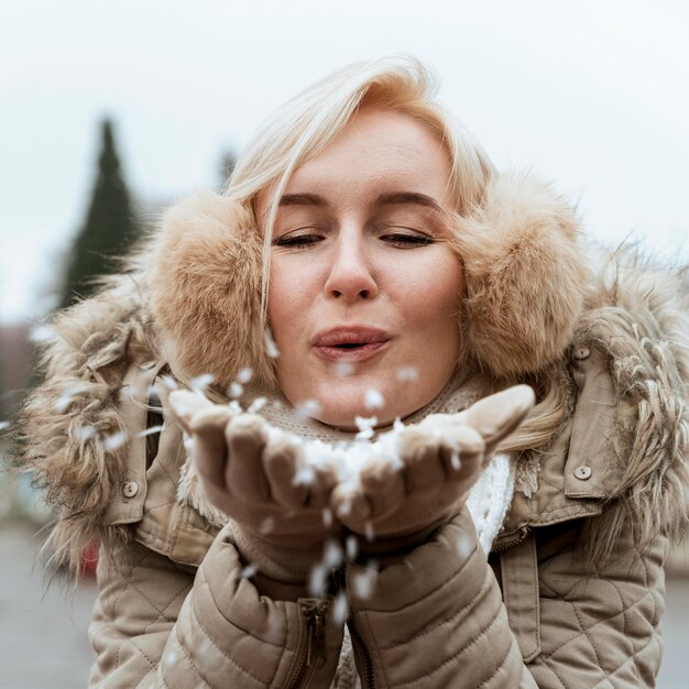 Dama en invierno soplando en la nieve.