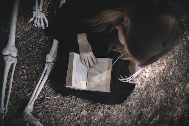 Dama de lectura con ropas oscuras cerca de los huesos