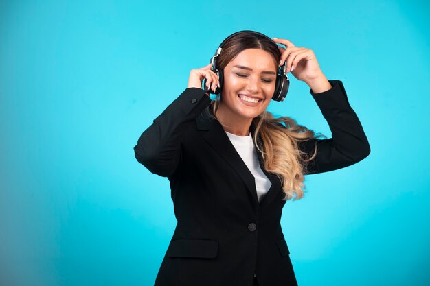 Dama de negocios en chaqueta negra con auriculares.