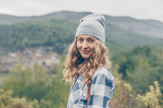 Foto gratuita dama de pie y sonriente en la naturaleza con sombrero gris y jeans durante el día