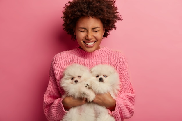 Foto gratuita dama de piel oscura mantiene los labios redondeados, quiere besar a una adorable mascota, juega con un pequeño cachorro