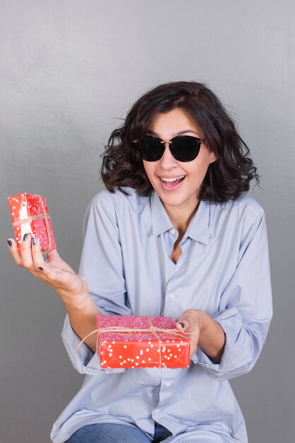 Dama sonriente en gafas de sol con regalos