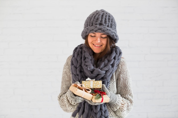 Foto gratuita dama sonriente en mitones, gorro y bufanda con un montón de cajas de regalo