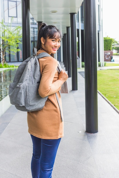 Dama sonriente con mochila y documentos.