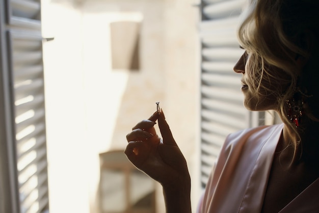 Dama con túnica de seda rosa tiene anillo de bodas en sus dedos