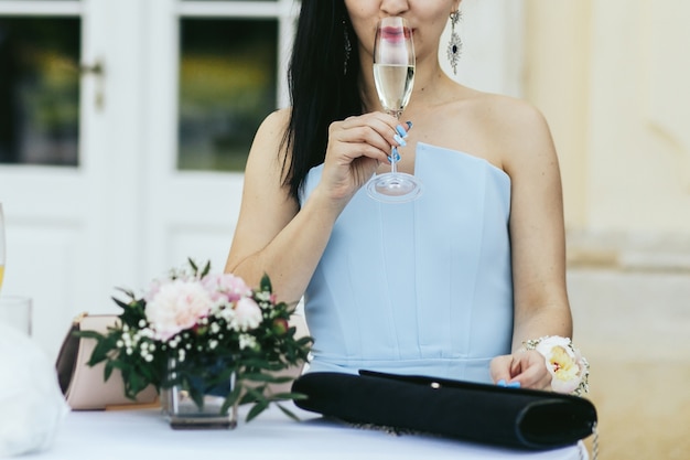 Foto gratuita la dama en vestido azul bebe champaña fría