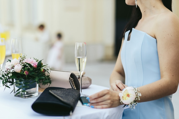 Foto gratuita dama en vestido azul con flores sobre su wirst se sienta a la mesa