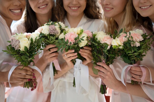 Damas de honor sonrientes con ramos de flores