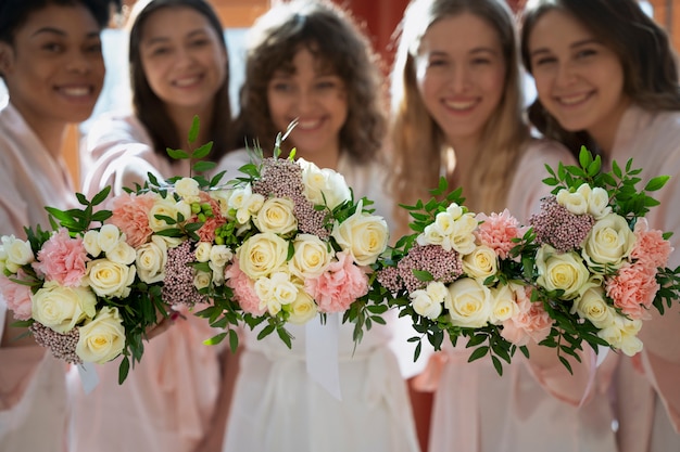 Damas de honor sonrientes de tiro medio con flores