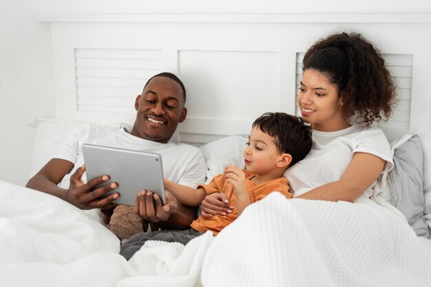 Dan leyendo algo en una tableta mientras está en la cama con su familia