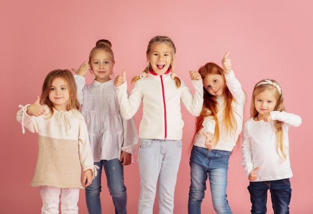 Dar y recibir regalos en Navidad. Grupo de niños sonrientes felices divirtiéndose, celebrando aislado sobre fondo rosa studio. Reunión de año nuevo 2021, infancia, felicidad, emociones.