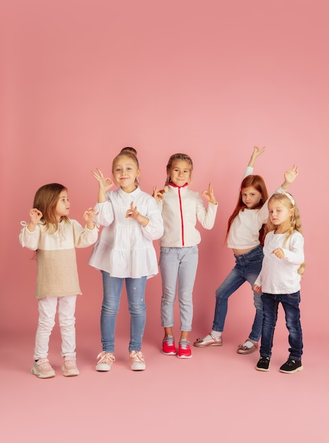 Dar y recibir regalos en Navidad. Grupo de niños sonrientes felices divirtiéndose, celebrando aislado sobre fondo rosa studio. Reunión de año nuevo 2021, infancia, felicidad, emociones.