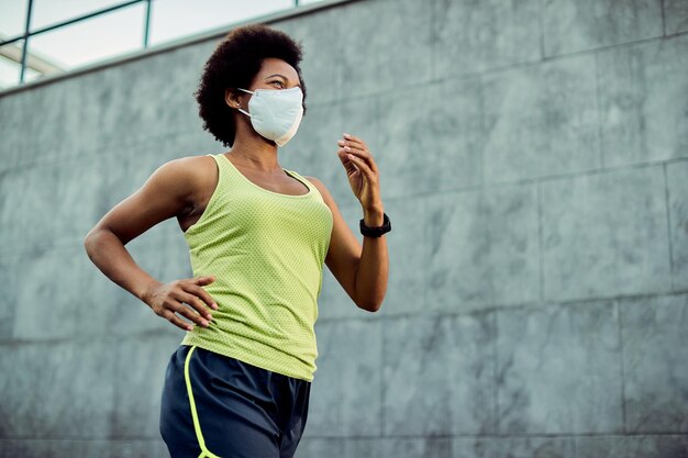 Debajo de la vista de una corredora negra con mascarilla protectora