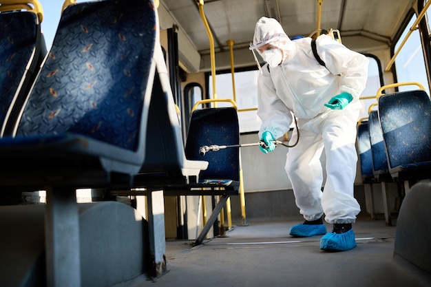 Debajo de la vista del hombre con traje protector que desinfecta el autobús público durante la pandemia del coronavirus