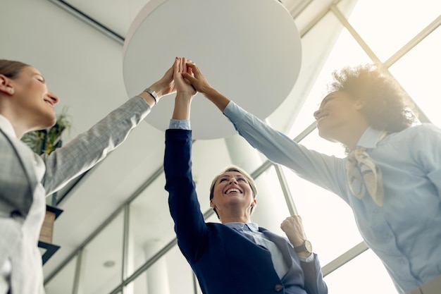 Debajo de la vista de mujeres empresarias felices juntando las manos en unidad