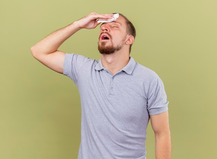 Foto gratuito débil joven apuesto enfermo eslavo secándose la frente con una servilleta con los ojos cerrados aislado sobre fondo verde oliva con espacio de copia