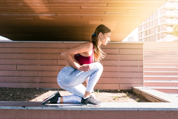 Decidido joven atleta femenina tomando posición para correr