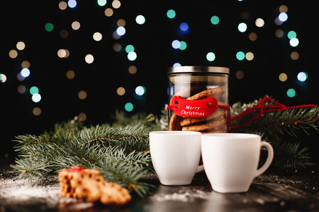 Decoración de año nuevo y navidad. Botella con galletas de chocolate y tazas para el té.