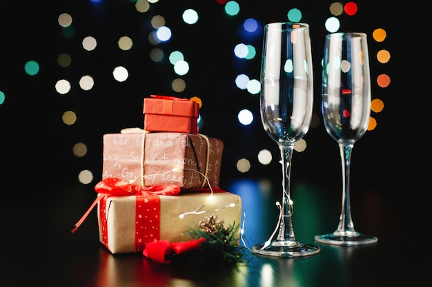 Decoración de año nuevo y navidad. Flautas de champán, pequeños regalos y ramas verdes.