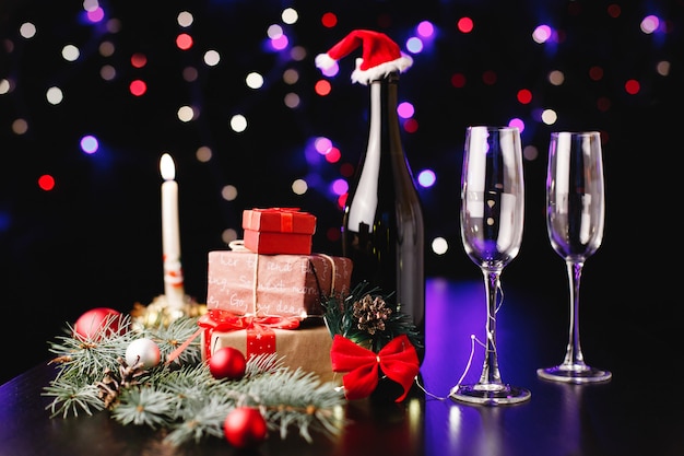 Decoración de año nuevo y navidad. Flautas de champán, pequeños regalos y ramas verdes.