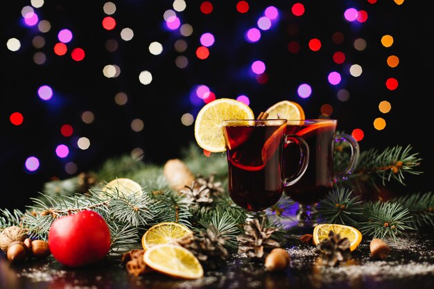 Decoración de año nuevo y navidad. Gafas con vino caliente sobre mesa con naranjas