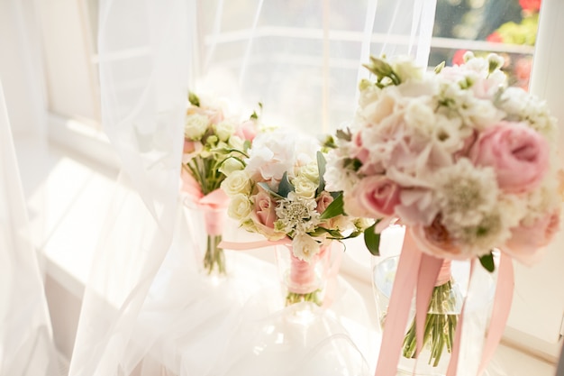 Decoración de la boda. Rosa brillante rosa ramo para una novia y damas de honor de pie delante de una ventana