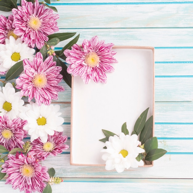 Decoración de flores con una caja vacía sobre fondo de madera