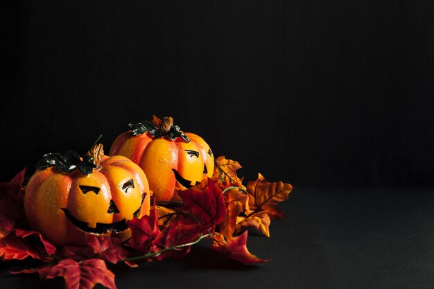 Decoración de halloween con dos calabazas y hojas de otoño