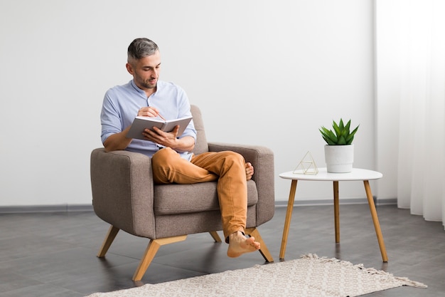 Decoración del hogar minimalista y hombre sentado en una silla con su agenda