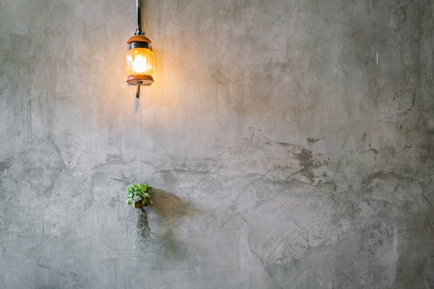 Decoración de la iluminación del vintage con la planta sobre la pared del cemento.