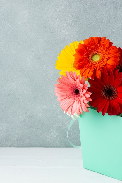 Decoración minimalista con flores de gerbera en un cubo.