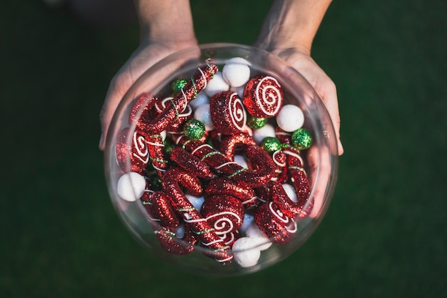 Decoración de navidad con manos sujetando contenedor de dulces