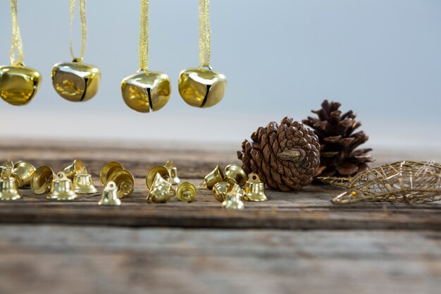 Decoración navideña dorada en una mesa de madera con piñas