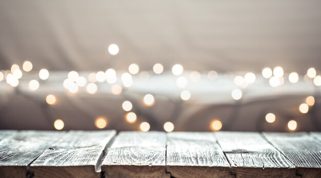 Decoración de pared de vacaciones de Navidad con mesa de madera vacía sobre luz festiva bokeh.