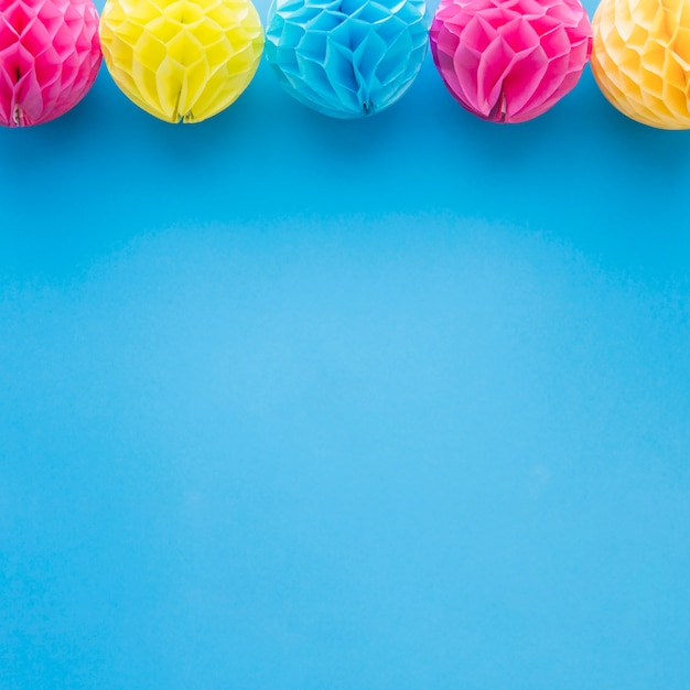 Decoración rosada y amarilla de las bolas del papel del pom-pom del panal en fondo azul