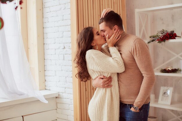 Decoración de vacaciones de invierno. Colores cálidos. Encantadora pareja joven se abraza tiernamente