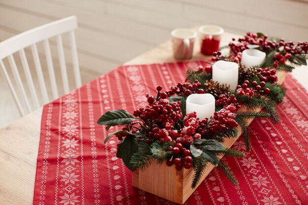 Decoración de vacaciones de invierno. Preparaciones de estudio. Plato de madera con frutos rojos y flores.