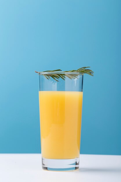 Decoración con vaso de zumo de naranja y hierbas.