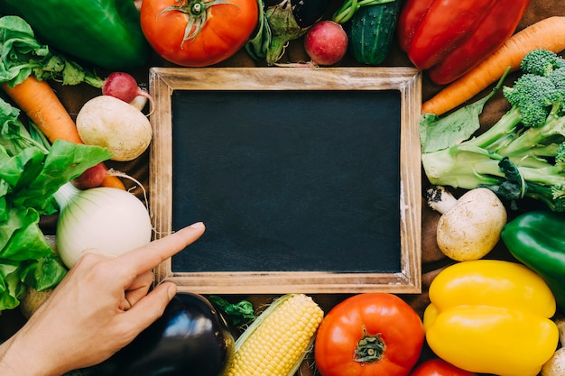 Decoración de verduras con mano apuntando hacia pizarra