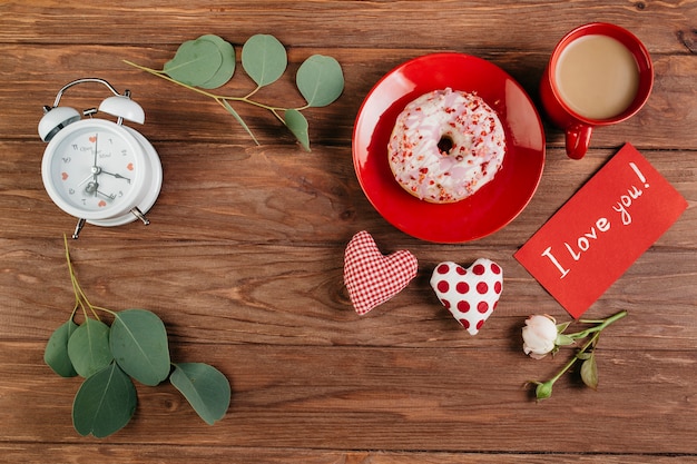Decoraciones del día de San Valentín cerca del desayuno con donut.
