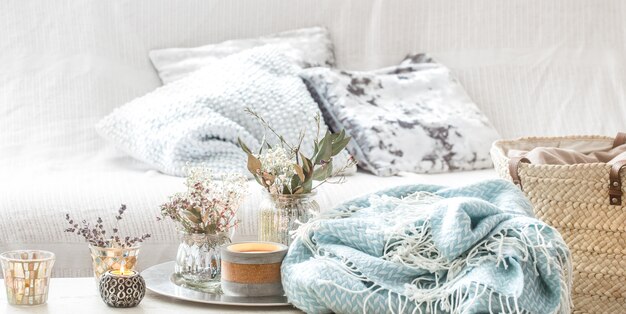 Decoraciones para el hogar en el interior. Una manta turquesa y una canasta de mimbre con un jarrón de flores y velas.