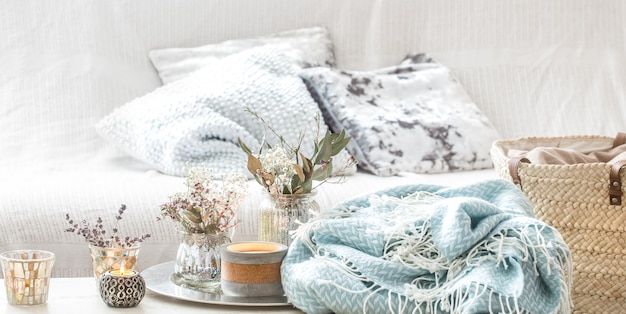 Decoraciones para el hogar en el interior. Una manta turquesa y una canasta de mimbre con un jarrón de flores y velas.