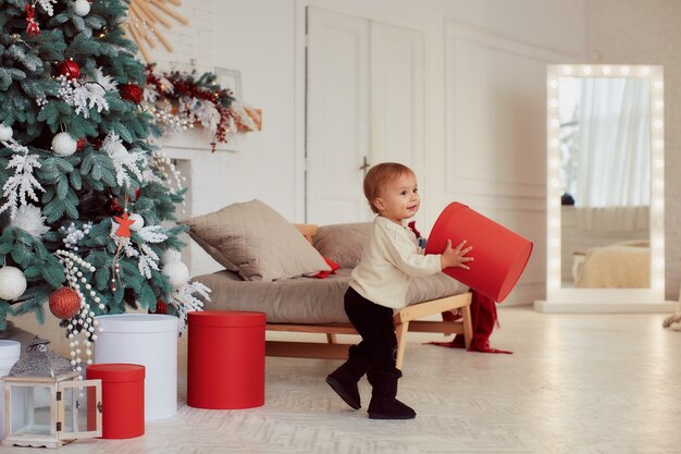 Decoraciones de vacaciones de invierno. Colores cálidos. Hermosa niña juega con las actuales cajas.