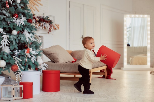 Decoraciones de vacaciones de invierno. Colores cálidos. Hermosa niña juega con las actuales cajas.