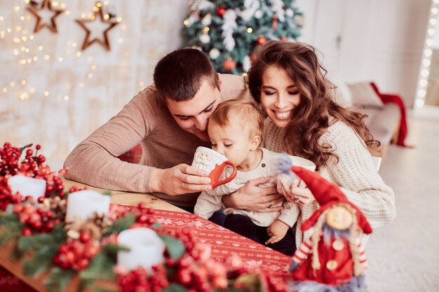 Decoraciones de vacaciones de invierno. Colores cálidos. Retrato familiar. Mamá, papá y su pequeña hija.