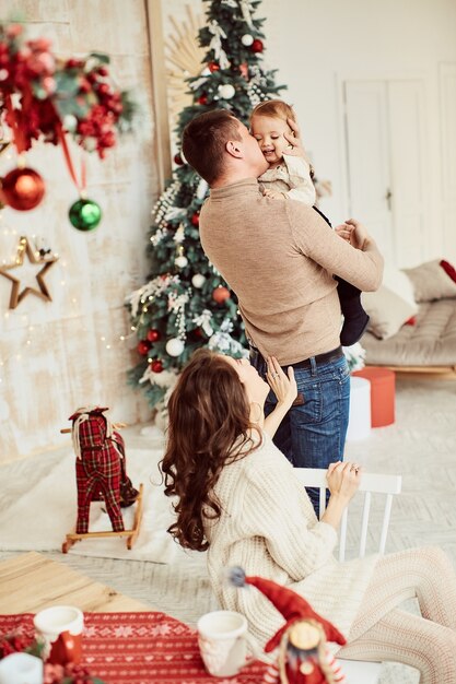 Decoraciones de vacaciones de invierno. Colores cálidos. Retrato familiar. Mamá, papá y su pequeña hija.