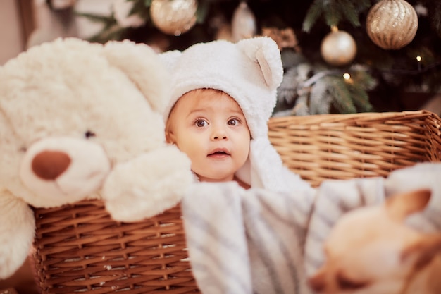 Decoraciones de vacaciones de invierno. Retrato de niña bebé. Niña encantadora en graciosas orejas blancas