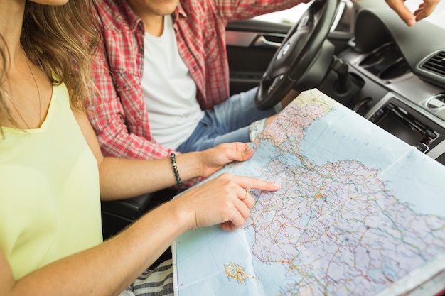 Dedo acusador de la mujer en el mapa de navegación de ubicación con el hombre en el coche