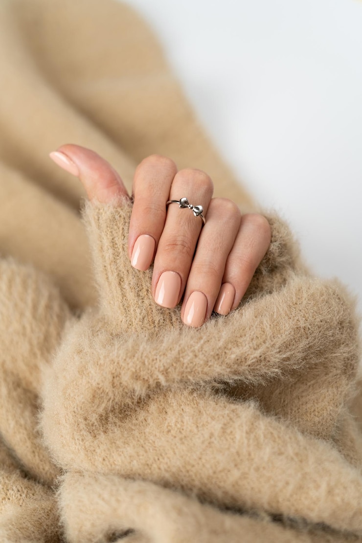 Foto gratuito dedos delgados y elegantes de una chica con una manicura desnuda pastel de moda y un suéter suave y esponjoso y un lindo lazo de plata